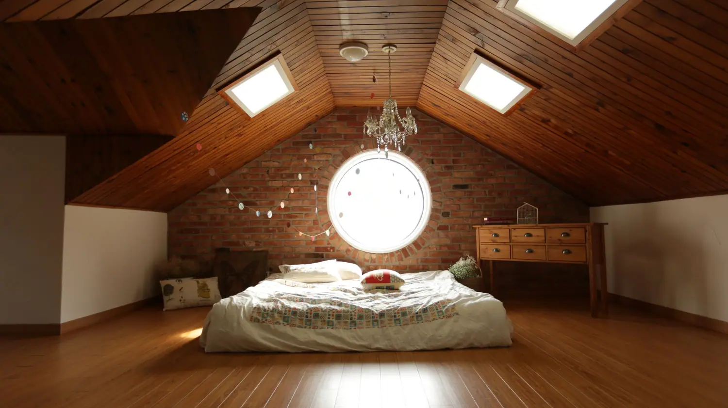Attic bedroom with a sloped wood ceiling, round window, and a small dresser